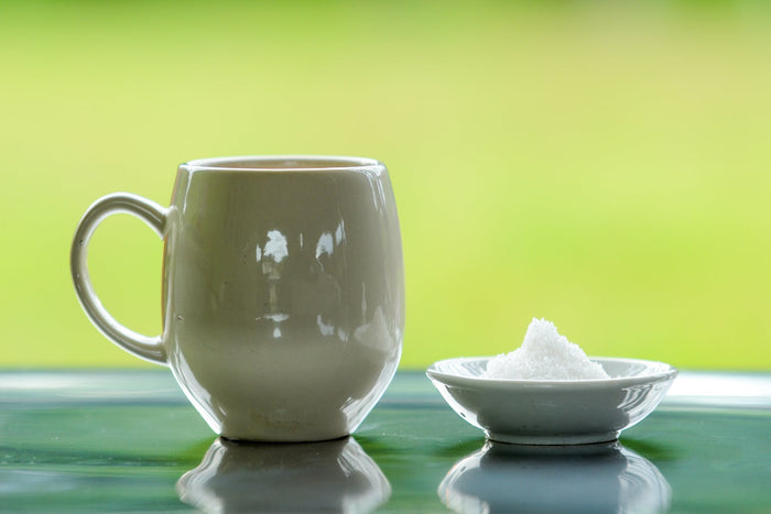 White-coffee-mug-and-collagen-powder-on-a glass-table-with-a-green-background 