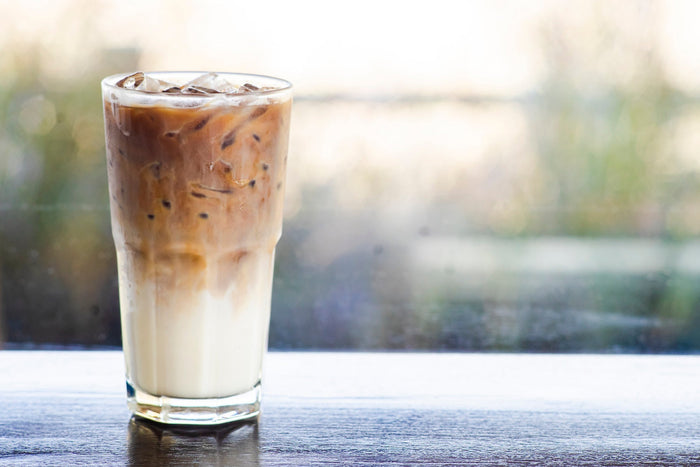 Glass of iced coffee with milk and ice cubes.