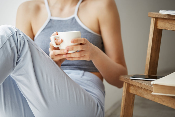 close up of a woman sitting on the floor holding a cup of coffee