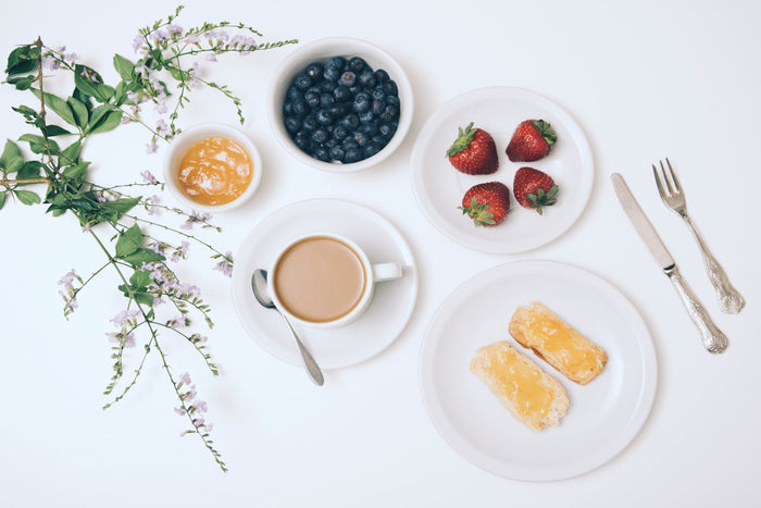 a breakfast made of berries, coffee and butter on a white background
