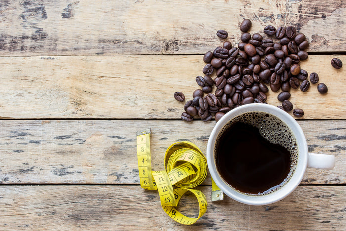 coffee beans and a cut of coffee and a measurement tape on a wooden table