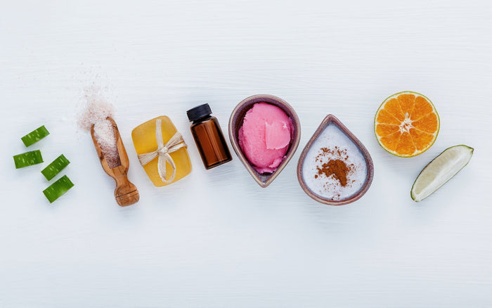 high-angle-view-food-table-aloe-vera-slices-sea salt-handmade-soap-essential-oil-pink-scrub-cinnamon-powder-and-fresh-citrus-fruits
