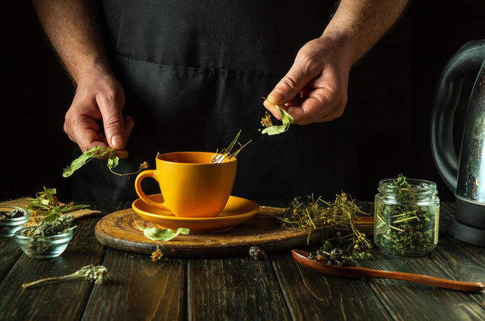 Man-preparing-tea-from-dried-medicinal-herbs-in-an-orange-cup