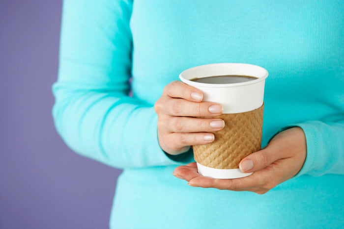 woman holding a cup of coffee and wearing a blue shirt