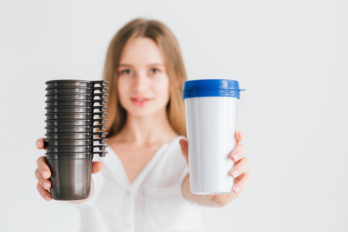 Woman holding energy drink cup and stack of coffee cups